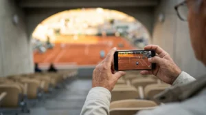 Apuestas de tenis en vivo: espectador siguiendo un partido en directo con móvil